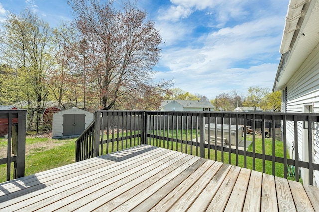 wooden terrace featuring a lawn, an outbuilding, a fenced backyard, and a shed