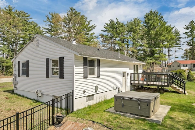 back of property with a lawn, fence, a hot tub, and a deck