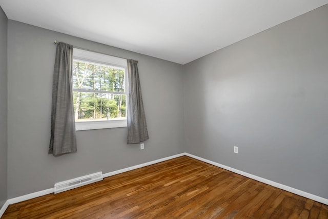 empty room with baseboards, wood finished floors, and visible vents