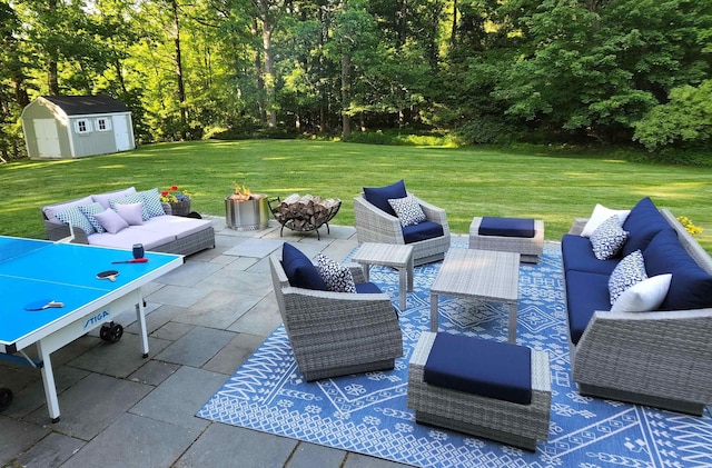view of patio / terrace featuring an outbuilding, a storage unit, and an outdoor living space with a fire pit