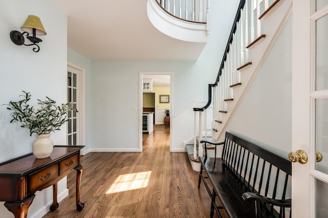 foyer entrance featuring baseboards, wood finished floors, and stairway