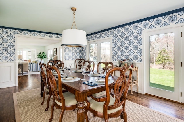 dining area featuring plenty of natural light, wood finished floors, a wainscoted wall, and wallpapered walls