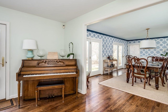 dining space featuring baseboards, wood finished floors, and wallpapered walls
