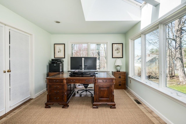 office area with a skylight, visible vents, and baseboards