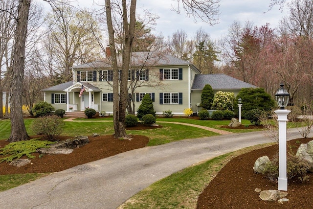 view of front of home featuring a front lawn, driveway, and a chimney