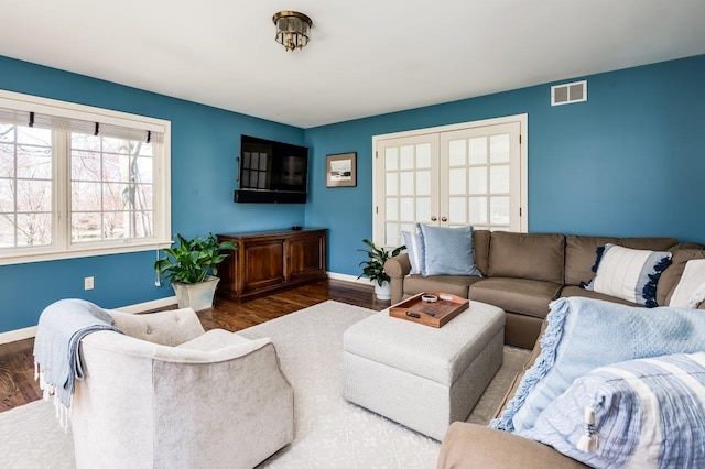 living room with visible vents, baseboards, and wood finished floors