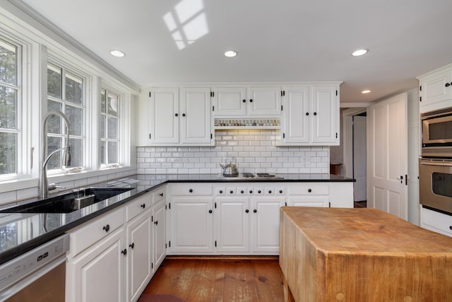 kitchen featuring tasteful backsplash, a sink, wood-type flooring, stainless steel appliances, and white cabinetry