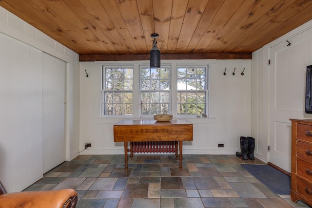 dining area with stone finish flooring, wood ceiling, and a decorative wall
