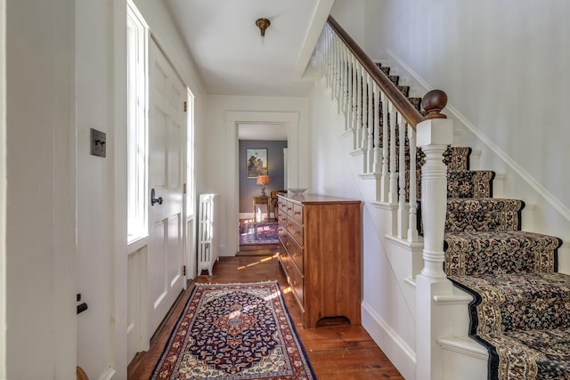 hall featuring stairs, radiator heating unit, and dark wood-type flooring