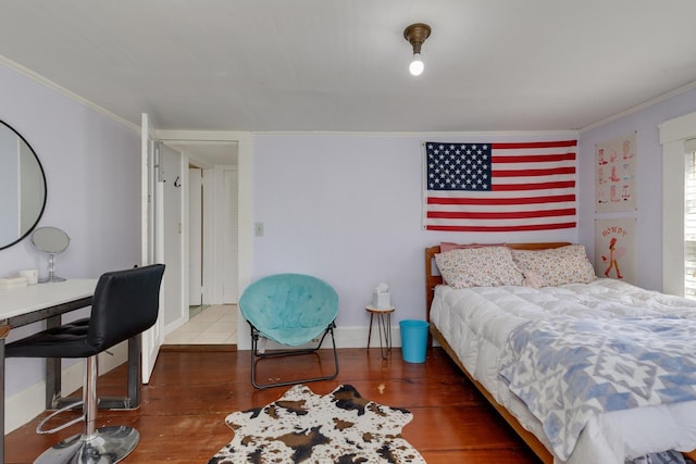 bedroom with crown molding, baseboards, and wood finished floors