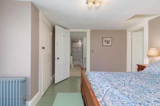 tiled bedroom featuring radiator heating unit, baseboards, and ensuite bath