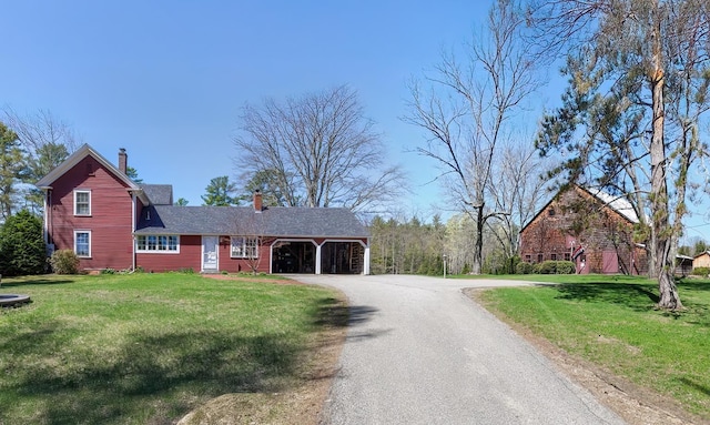 view of front facade featuring a garage, driveway, a chimney, and a front lawn