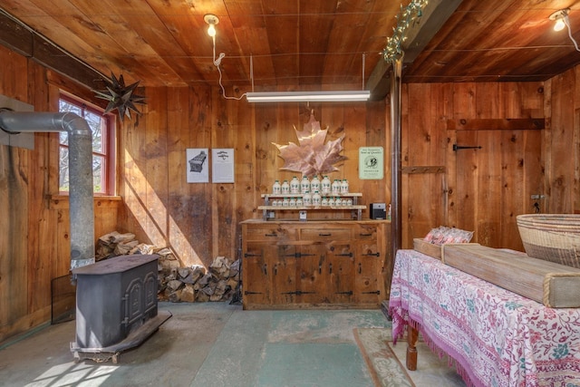 bedroom featuring wood walls, concrete floors, a wood stove, and wooden ceiling