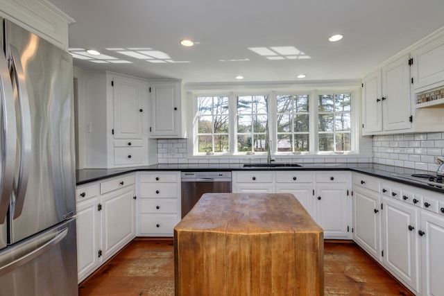kitchen featuring stainless steel appliances, dark countertops, a wealth of natural light, and a sink