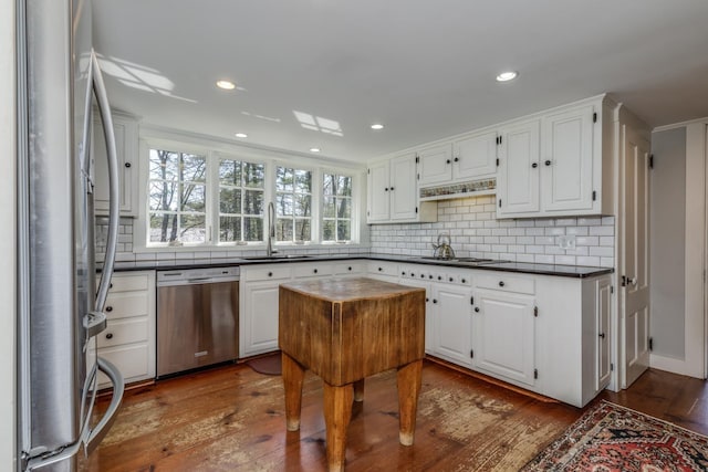 kitchen featuring a sink, appliances with stainless steel finishes, backsplash, and dark countertops