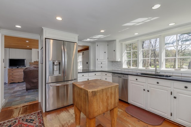 kitchen with a sink, appliances with stainless steel finishes, white cabinets, and decorative backsplash