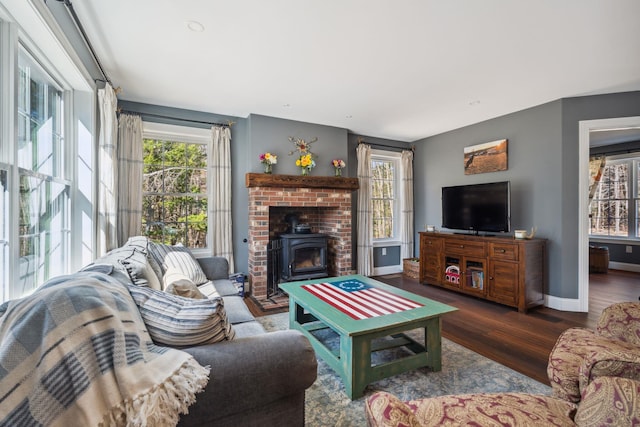 living room with baseboards, a wood stove, and wood finished floors