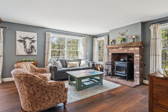 living room featuring baseboards, a wood stove, and wood finished floors