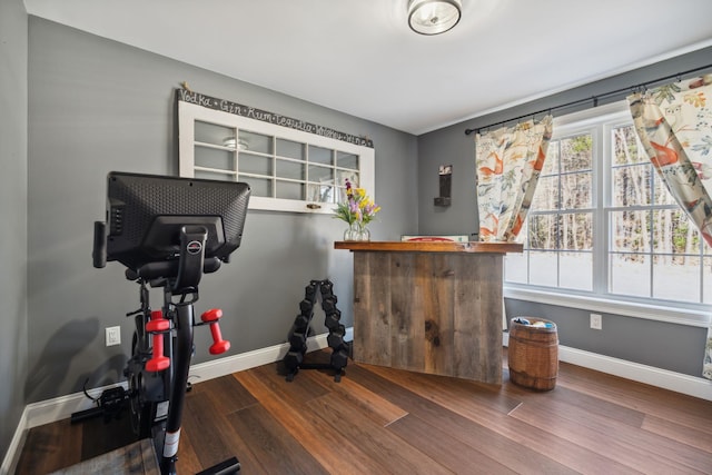 bar with baseboards, wood finished floors, and a bar