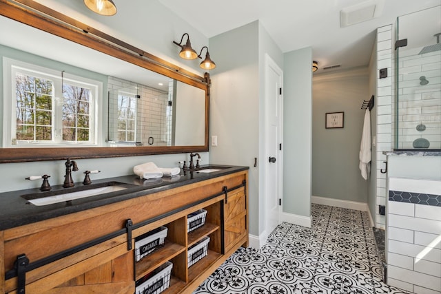 bathroom with a sink, baseboards, tiled shower, and visible vents