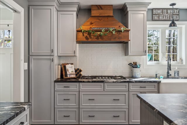 kitchen featuring a sink, stainless steel gas cooktop, premium range hood, tasteful backsplash, and gray cabinetry