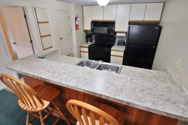 kitchen featuring a sink, white cabinets, a breakfast bar area, and black appliances