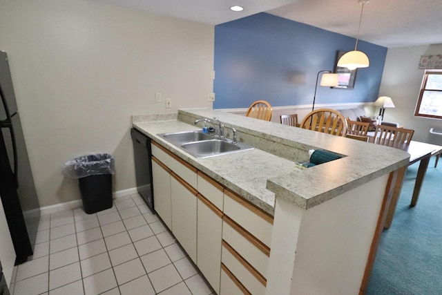 kitchen with a sink, light countertops, a peninsula, decorative light fixtures, and black appliances