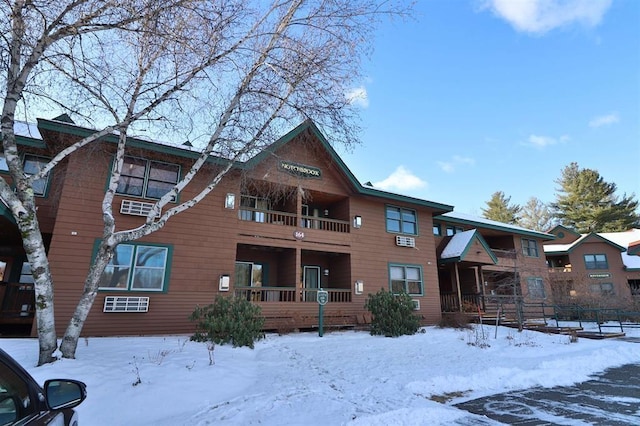 snow covered back of property featuring a balcony