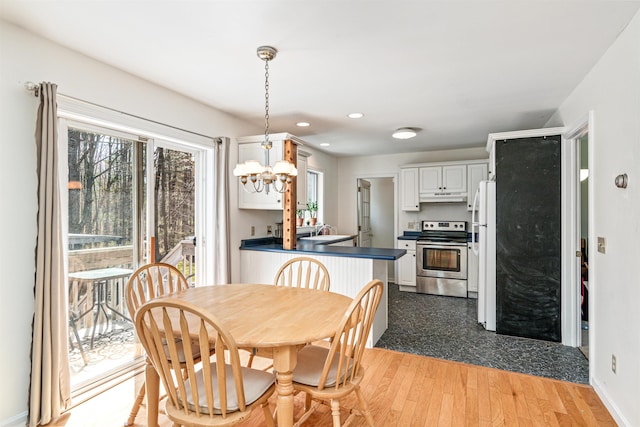 dining space featuring light wood-style floors, baseboards, recessed lighting, and a chandelier