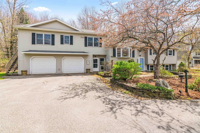 view of front of home featuring a garage, stairs, and aphalt driveway