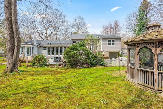 rear view of house featuring a gazebo, fence, a yard, and a chimney