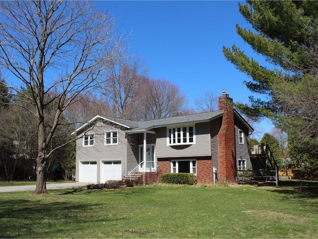 bi-level home featuring an attached garage, driveway, a chimney, and a front lawn