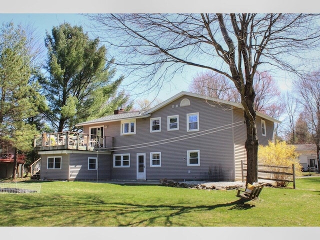 rear view of property with a balcony, a yard, and a chimney