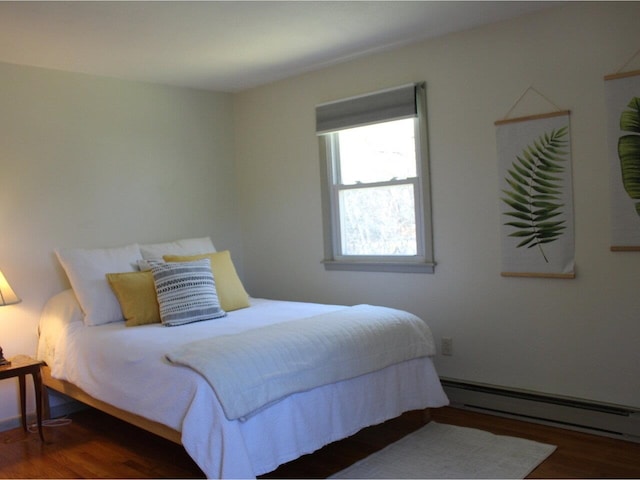bedroom with baseboard heating and wood finished floors