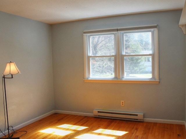 spare room featuring baseboard heating, light wood-style flooring, and a wealth of natural light