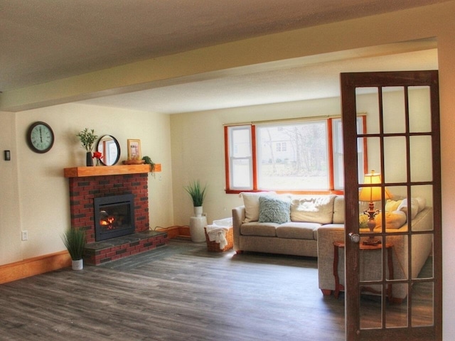 living area with baseboards, a brick fireplace, and wood finished floors