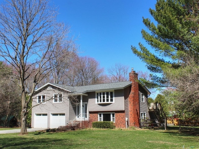 raised ranch with concrete driveway, a garage, a chimney, and a front lawn