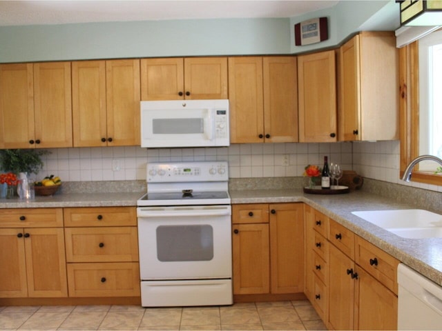 kitchen with white appliances, backsplash, a sink, and light countertops