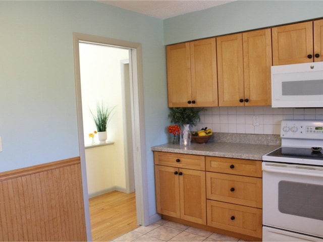 kitchen with light countertops, a wainscoted wall, tasteful backsplash, and white appliances