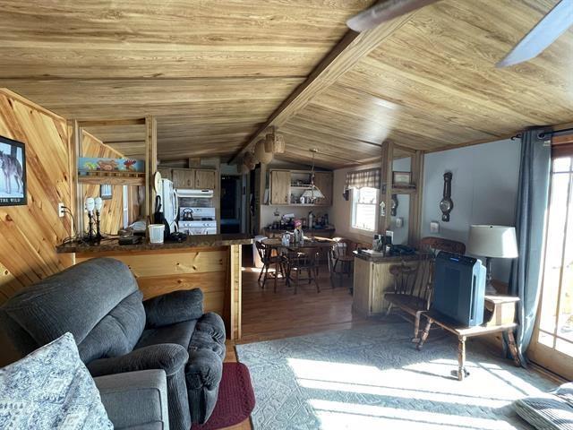 living room with wooden ceiling, vaulted ceiling, and wood finished floors