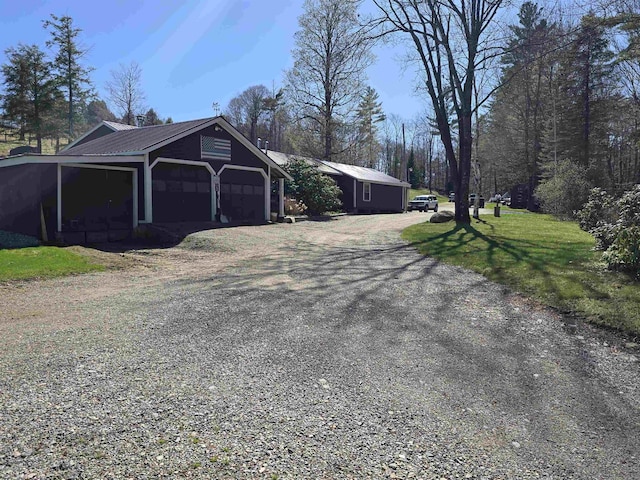 view of side of home with a garage, dirt driveway, and metal roof