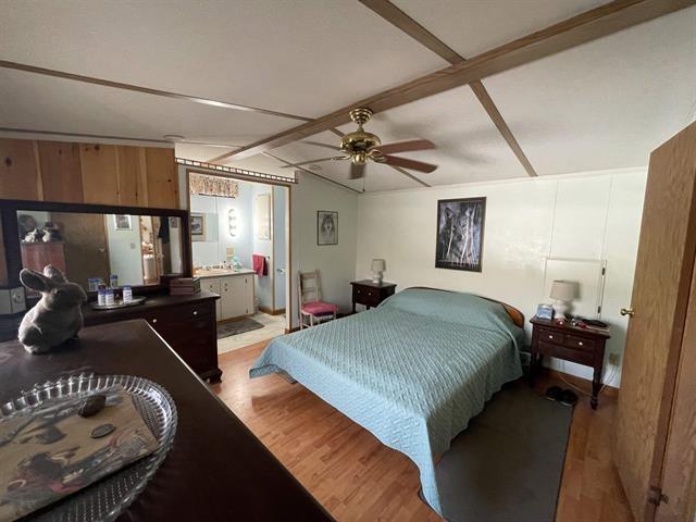 bedroom with lofted ceiling with beams and light wood-style flooring