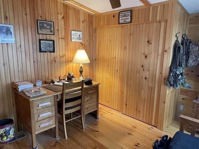 home office featuring light wood-style floors, wooden walls, and visible vents