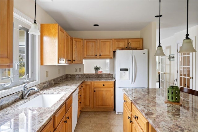 kitchen with a sink, pendant lighting, white appliances, and light stone countertops