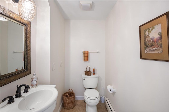 half bath with tile patterned flooring, toilet, baseboards, a baseboard radiator, and a sink