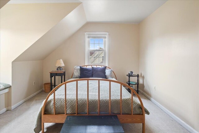 carpeted bedroom featuring baseboards and lofted ceiling