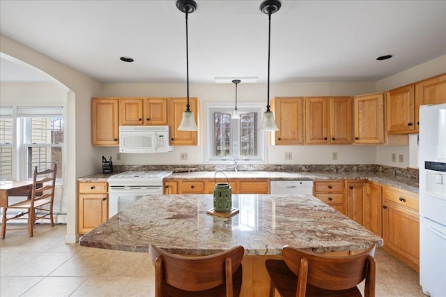 kitchen with white appliances, a kitchen breakfast bar, arched walkways, and a healthy amount of sunlight