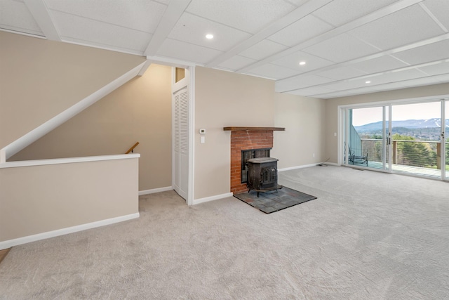 unfurnished living room with carpet floors, recessed lighting, baseboards, and a wood stove