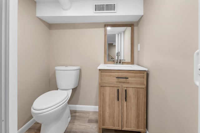 bathroom with visible vents, vanity, wood finished floors, toilet, and baseboards