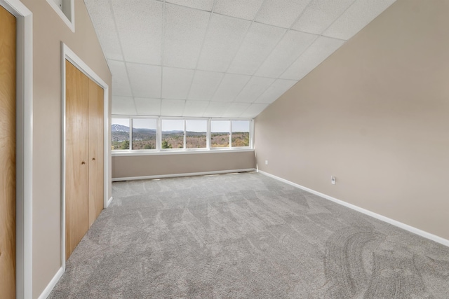 empty room featuring carpet floors, baseboards, and a drop ceiling